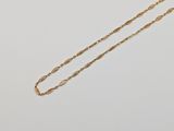 a gold necklace with a long chain that has been set on top of a white surface