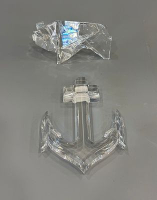 une ancre transparente et un anneau en argent posés sur une table