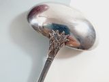 a silver spoon with a flower on it on a white surface