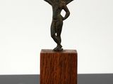 une image représentant une statue en bronze d'un homme posée sur un socle en bois