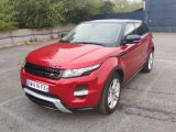Le Range Rover rouge est garé sur un parking devant un immeuble.