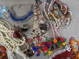 many different types of necklaces and bracelets laid out on a table