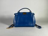 a small blue handbag with a gold chain on a white background
