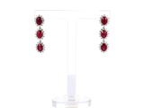 une paire de boucles d'oreilles en rubis et diamants posée sur un socle en acrylique transparent