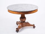 une table à plateau rond en marbre, montée sur roulettes et dotée d'un piètement en bois