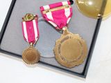 two medals and a gold ball in a black box