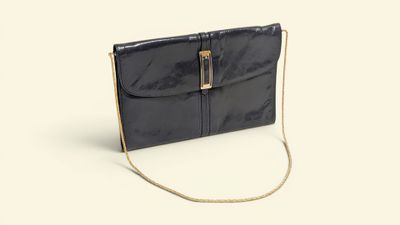 the black clutch bag is on a white surface with a chain around it