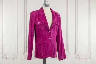 a pink jacket on a mannequin stand in front of a white wall