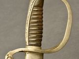 a close up of a sword with a gold handle on a gray background