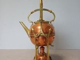 a tea pot on a stand with a tea kettle on it