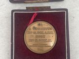 a gold medal in a case with a red ribbon around it
