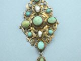 a close up of a broochee with turquoise and white stones