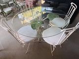 une table en verre avec quatre chaises et un vase posé dessus