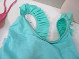 a blue bikini with ruffles on it next to a pair of pink shoes