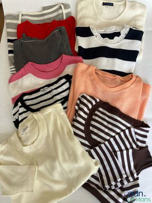Plusieurs pulls et shorts sont étalés sur un lit