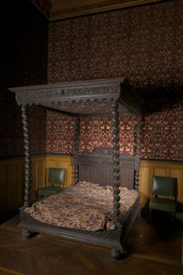 un lit à baldaquin dans une chambre aux murs lambrissés