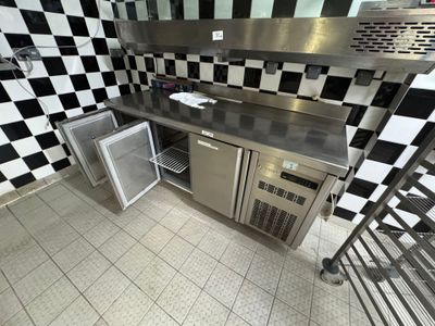 une cuisine avec un mur à carreaux et des plans de travail en inox