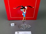 figurine of a man with a bird on his head and a dice in front of a red box