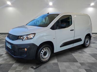 Une camionnette blanche est garée dans une pièce au sol carrelé en damier.