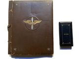 un vieux livre à la couverture en cuir posé à côté d'un livre orné d'un emblème représentant un avion