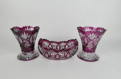trois vases en verre violet posés les uns à côté des autres sur une surface blanche