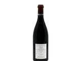 the bottle of red wine is sitting on a white surface