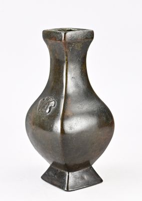 un vase en métal posé sur une surface blanche