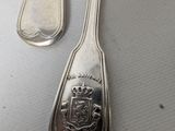 a silver spoon with a crown on it next to other silver spoons