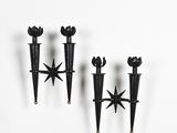 three black candle holders on a white wall with a star on one of them