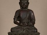 statue d'un Bouddha assis sur une fleur de lotus, dont le reflet se dégage sur une surface en verre