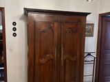 a wooden armoire in a room with a chandelier hanging from the ceiling