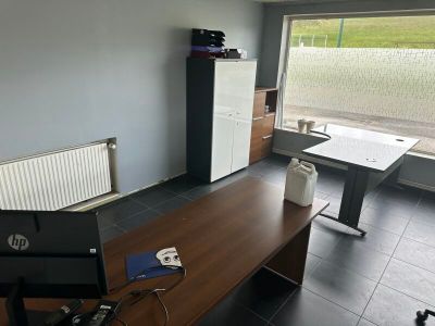 un bureau sur lequel est posé un ordinateur portable, dans une pièce dotée d'une grande fenêtre