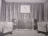 a black and white photo of a living room with two chairs and a cabinet