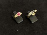 pair of gold rings with a pink stone on a black surface