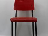 red chair against a white wall with a black metal frame