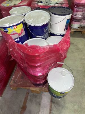 de nombreux seaux de peinture posés sur une palette dans un entrepôt