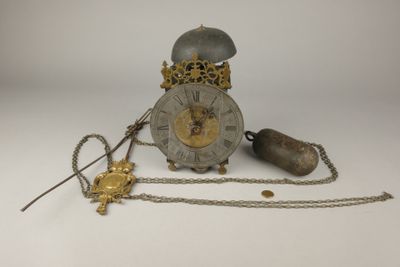 une horloge entourée d'une chaîne, posée sur une surface blanche