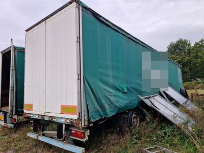un camion dont l'arrière est recouvert d'une bâche, garé dans un champ