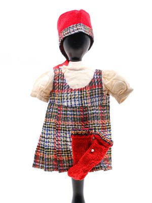 un mannequin coiffé d'un chapeau rouge et vêtu d'une robe à carreaux