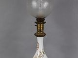 a white and gold lamp with a glass shade on top of it