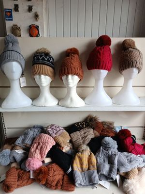 many hats and mittens on display on a shelf