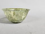 a green glass bowl sitting on a white surface