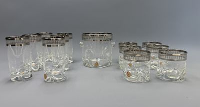 six verres aux bords argentés sont alignés sur une surface blanche