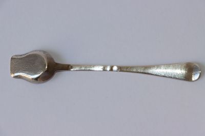 une cuillère et un repose-cuillère sur une surface blanche