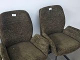 two brown chairs sitting next to each other on a tiled floor