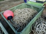 une caisse verte remplie de cordes à côté d'une bouée rouge
