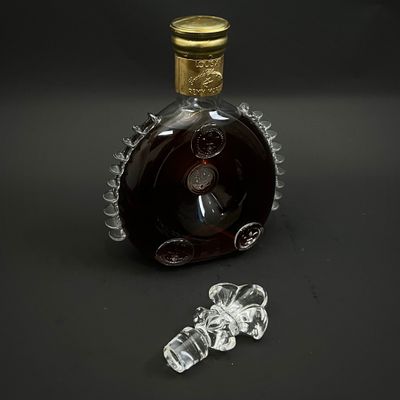 une bouteille d'alcool posée sur une table, à côté d'un bouchon en verre