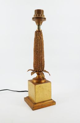 a gold colored lamp with a wooden base and a rope wrapped around the base
