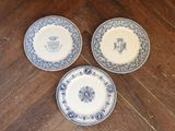 three blue and white plates sitting on top of a wooden table