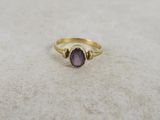 gros plan d'une bague en or avec une pierre violette